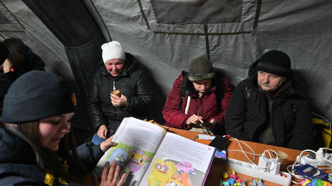 Families and individuals share a simple meal inside the tent, finding temporary relief from the heavy frost as recovery efforts continue after overnight missile and drone strikes