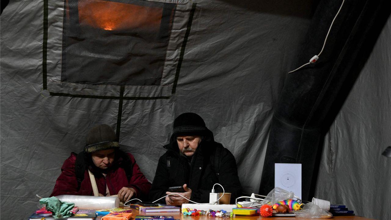 Inside a heated tent known as a “Point of Invincibility,” people sit and rest while charging their electronic devices, established across Ukraine during blackouts
