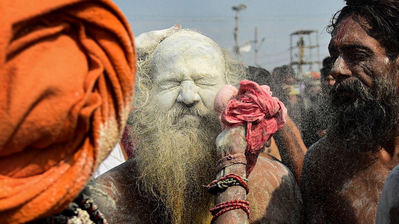 A Naga sadhu of 'Shri Panch Dashnam Avahan Akhara' gets sacred ashes, commonly called 'bhasma', applied to his face by another sadhu as they arrive to offer prayers and take a holy dip in the river Ganga during the Magh Mela festival. PICS/PTI