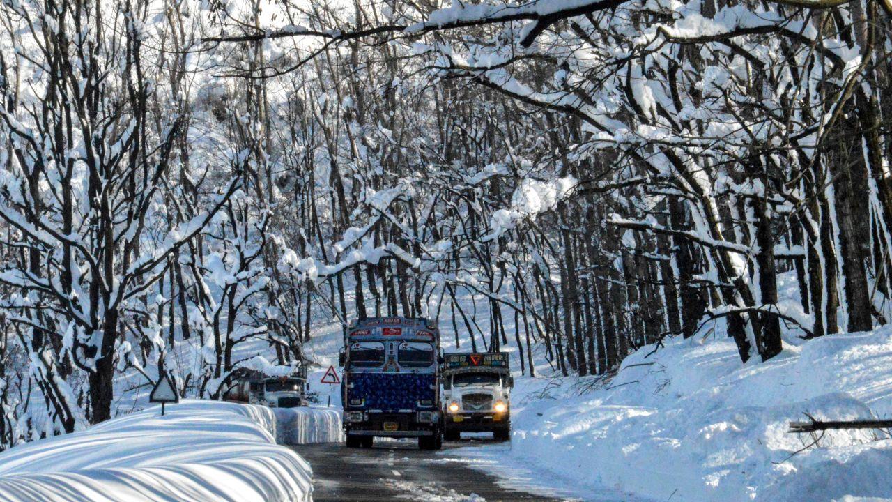 Oil tankers move via the old national highway, passing through snow-covered trees after heavy snowfall