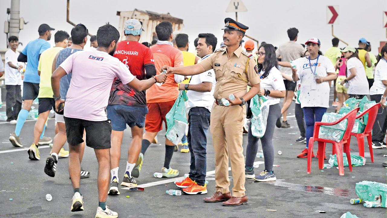 A police officer hands out bottled water to Full Marathon runners at the Bowstring Arch Bridge on the Coastal Road during the Tata Mumbai Marathon 2026 on Sunday, highlighting the coordinated efforts of civic agencies and volunteers in ensuring the smooth conduct of the event. Pic/ASHISH RAJE