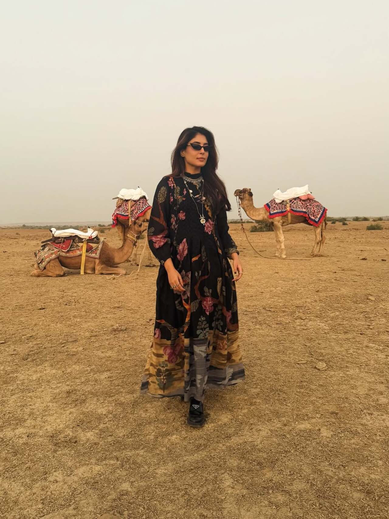 Kritika Kamra struck a stylish pose at a desert setting, surrounded by camels. She enjoyed the scenic landscape in a black printed dress.