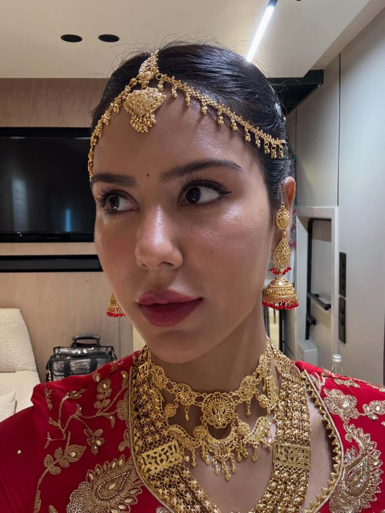 The close-up shot highlights Sonam Bajwa’s exquisite bridal jewellery, with a delicate gold maang tikka framing her forehead and statement jhumkas adding elegance to her look.