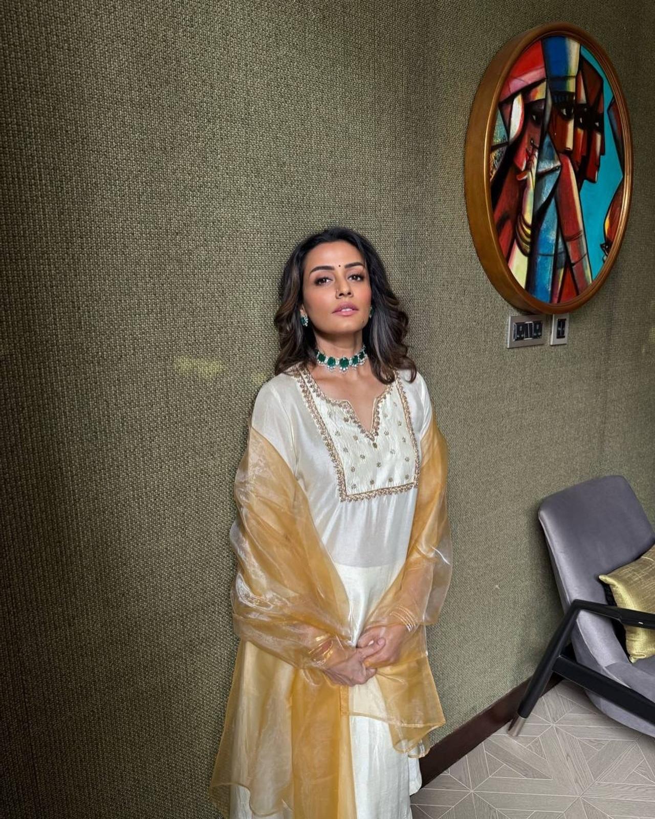 She looks ethereal in acwhite satin silk suit with gold embroidery, paired with a golden organza dupatta. The emerald choker necklace gives it an elegant touch.