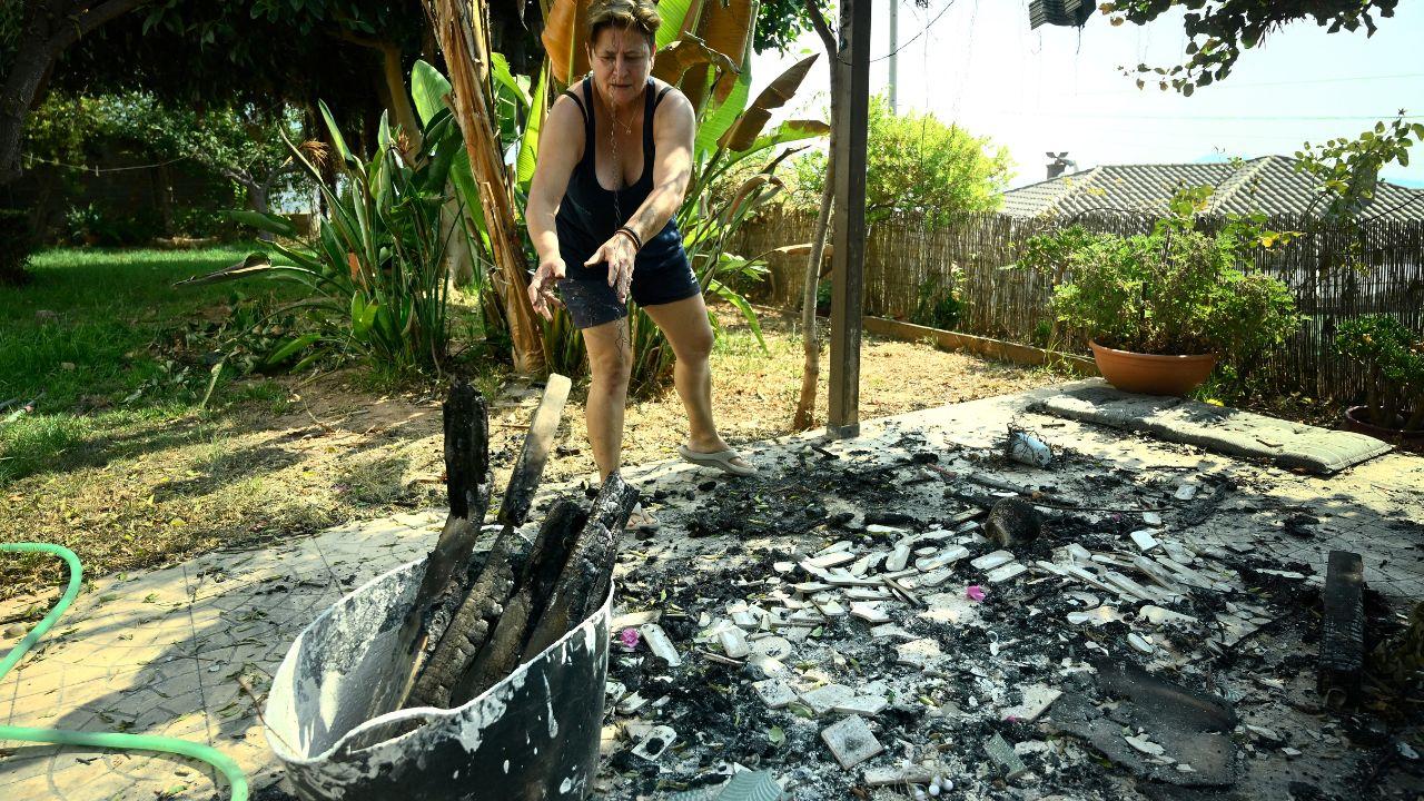 A woman cleans her garden after a wildfire swept through La Vall d'Uix&oacute;, about 55 kilometres northeast of Valencia, Spain. The wildfires have forced around 60,000 people to evacuate after burning through nearly 77,000 hectares (1.90 lakh acres) of land in Spain&mdash;an area almost the size of New York City