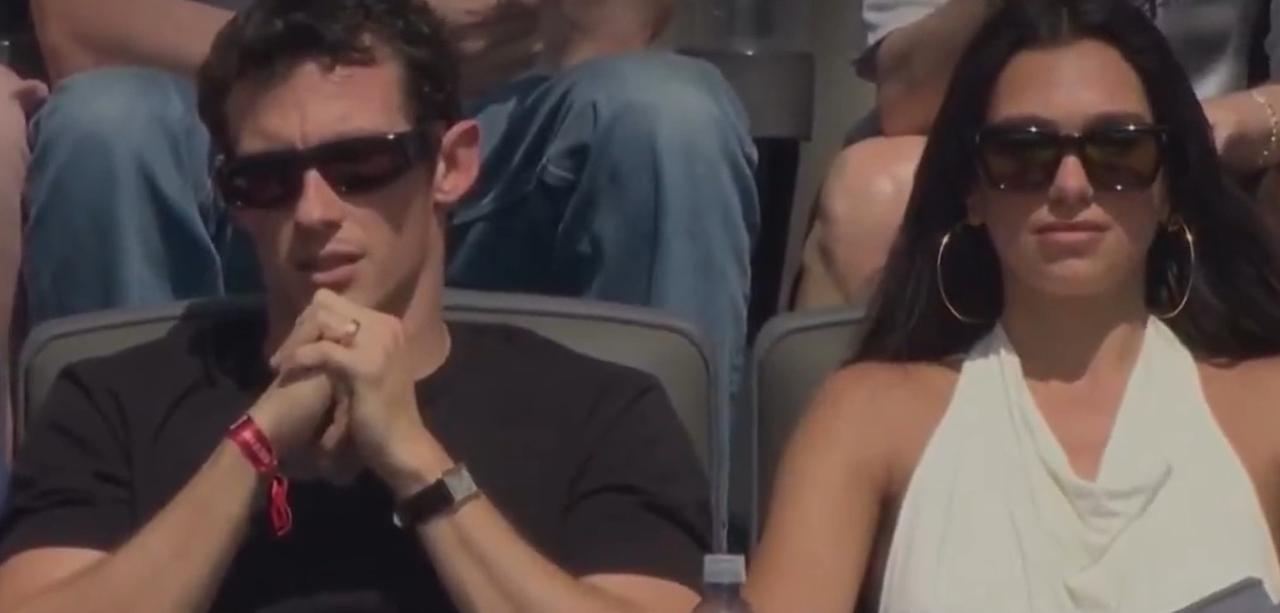 Dua Lipa and Callum Turner pick contrasting outfits for the match. Dua shines in her white halter top and Callum picks a simple black tee&nbsp;