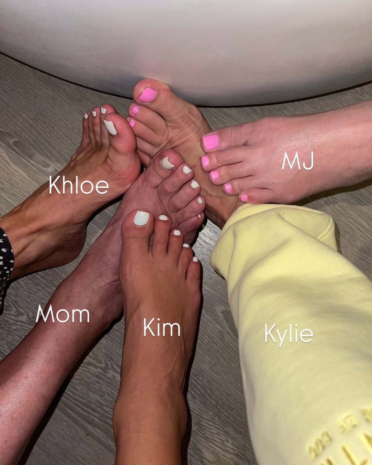 A close-up image shows the feet of four family members labeled "Khloe," "Mom," "Kim," and "MJ," each displaying freshly painted toenails in white or pink shades.