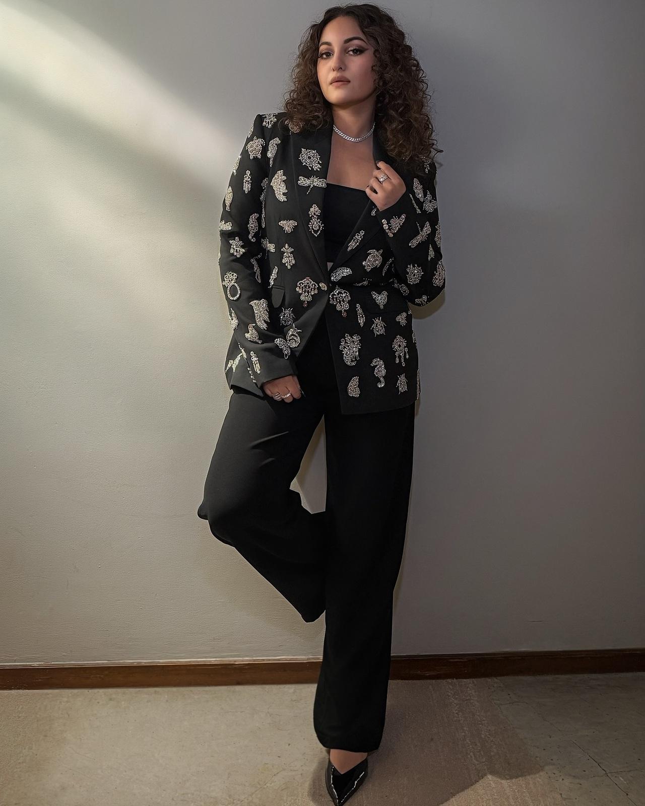 Sonakshi exudes boss-lady energy in a black pantsuit adorned with silver embellishments. Paired with pointed heels and minimal jewellery, the look balances power dressing and glamour. Sonakshi exudes boss-lady energy in a black pantsuit adorned with silver embellishments. Paired with pointed heels and minimal jewellery, the look balances power dressing and glamour.
