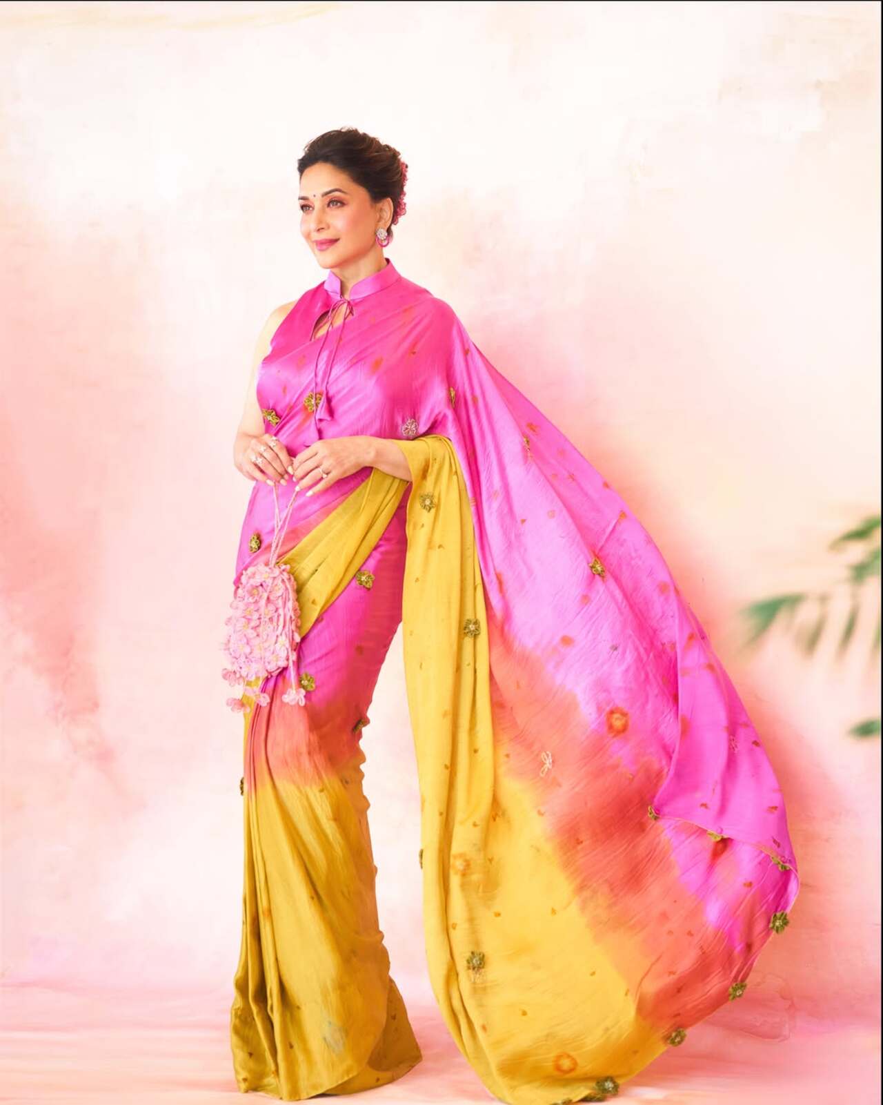 Madhuri Dixit channels ethereal grace in a striking tie-and-dye ombre saree that seamlessly blends vibrant pink and mustard yellow tones.