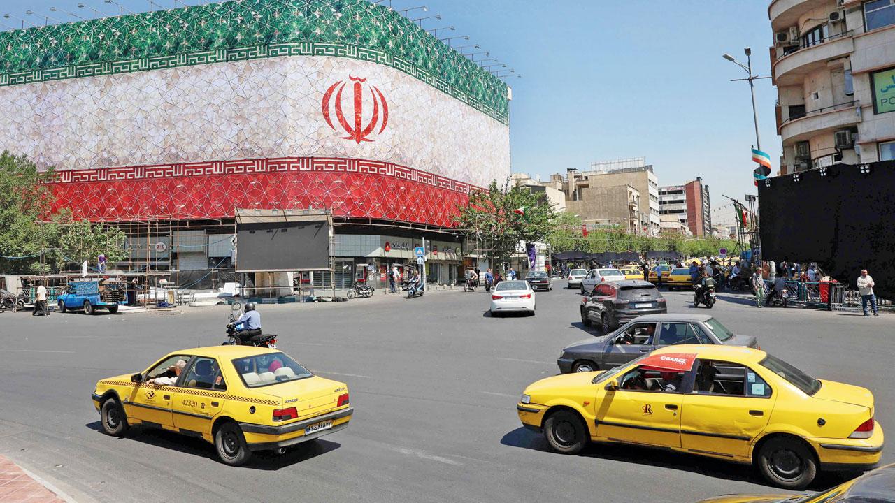 Traffic moves past the Iranian national flag displayed on a building at Enghelab square in Tehran. Pic/AFP