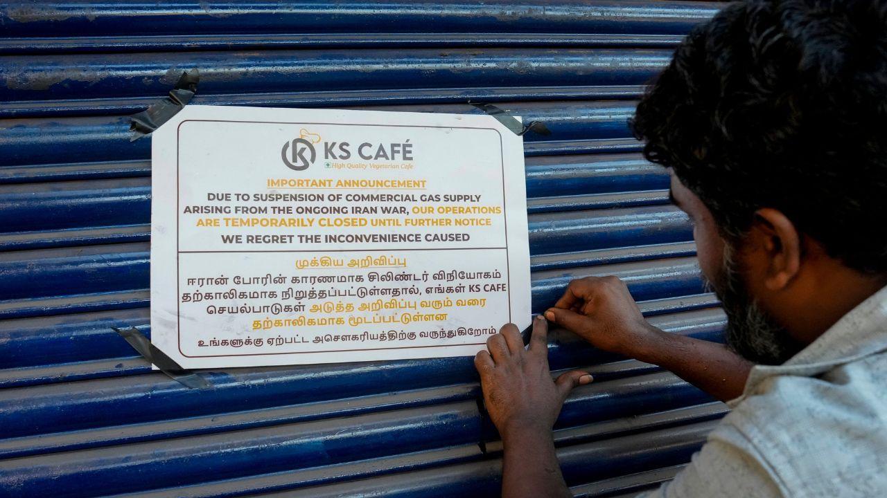 A man pastes a notice on the shutter of a restaurant announcing temporary closure due to shortage of commercial liquefied petroleum(LPG) gas cylinders in Chennai