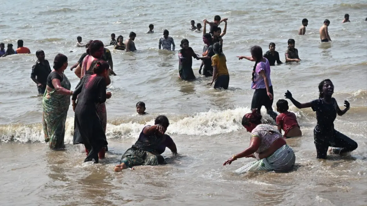 Friends gather by the sea, laughing and dancing as colours paint the sands of Juhu
