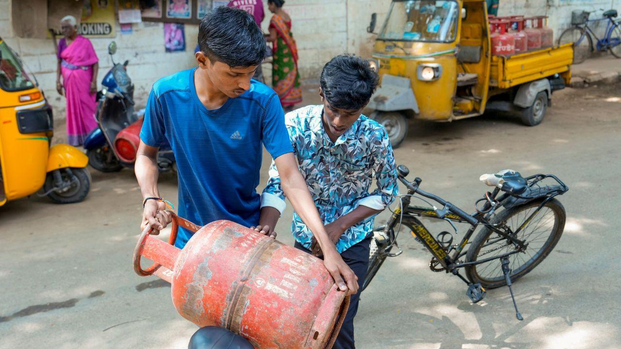 Delivery personnel prepare to carry an LPG cylinder on a cycle amid an ongoing LPG supply shortage in the country, in Chennai