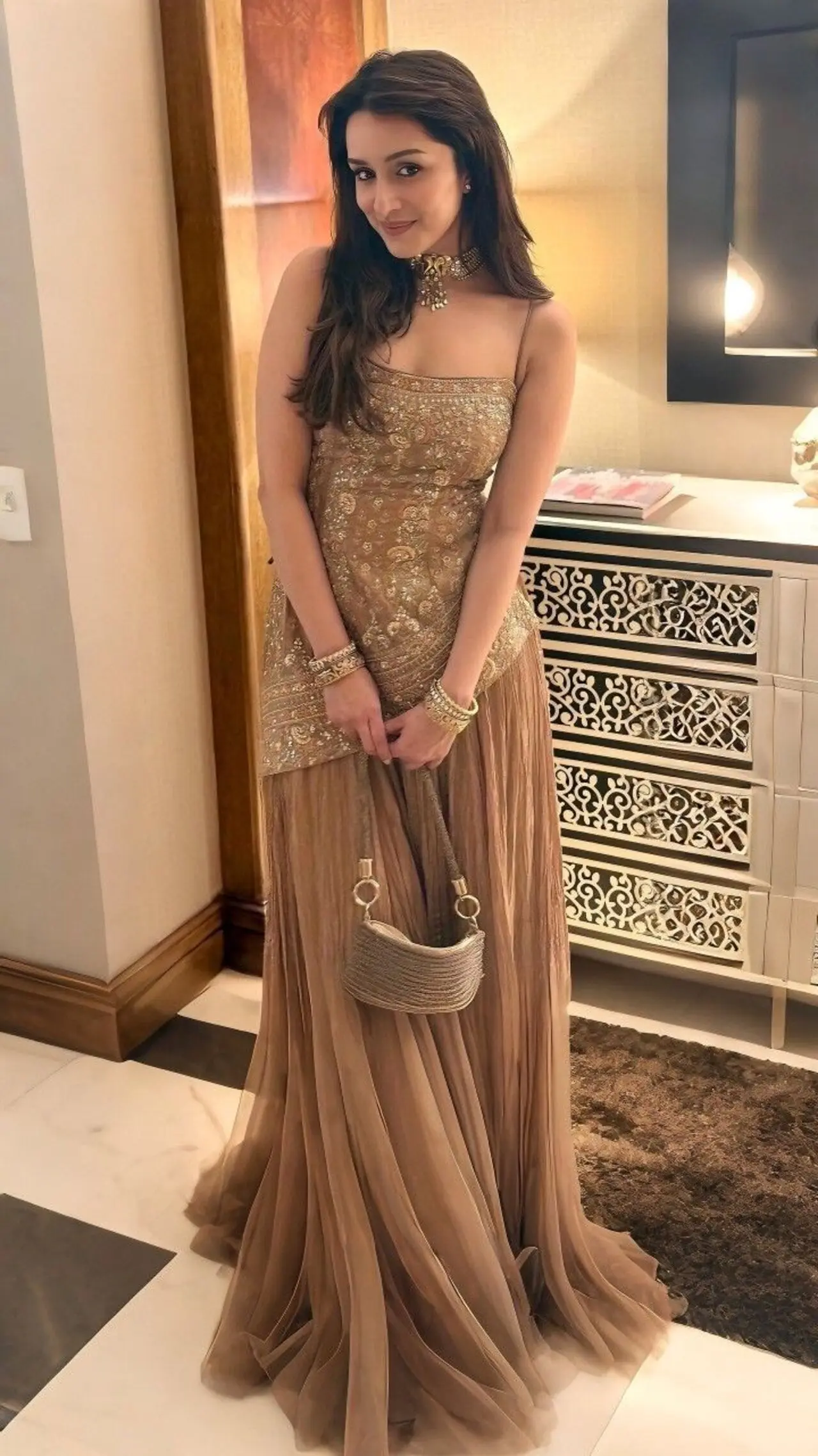 Shraddha Kapoor brings playfulness and elegance in this golden Naushaba embroidered sharara set featuring a sleeveless asymmetrical top and tule pants.
