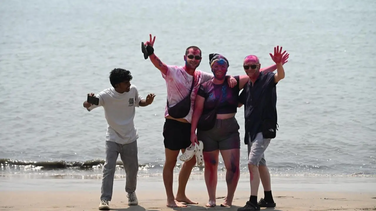 A young Mumbaikar poses with foreign visitors as colours and smiles bring everyone together at Chowpatty during Holi