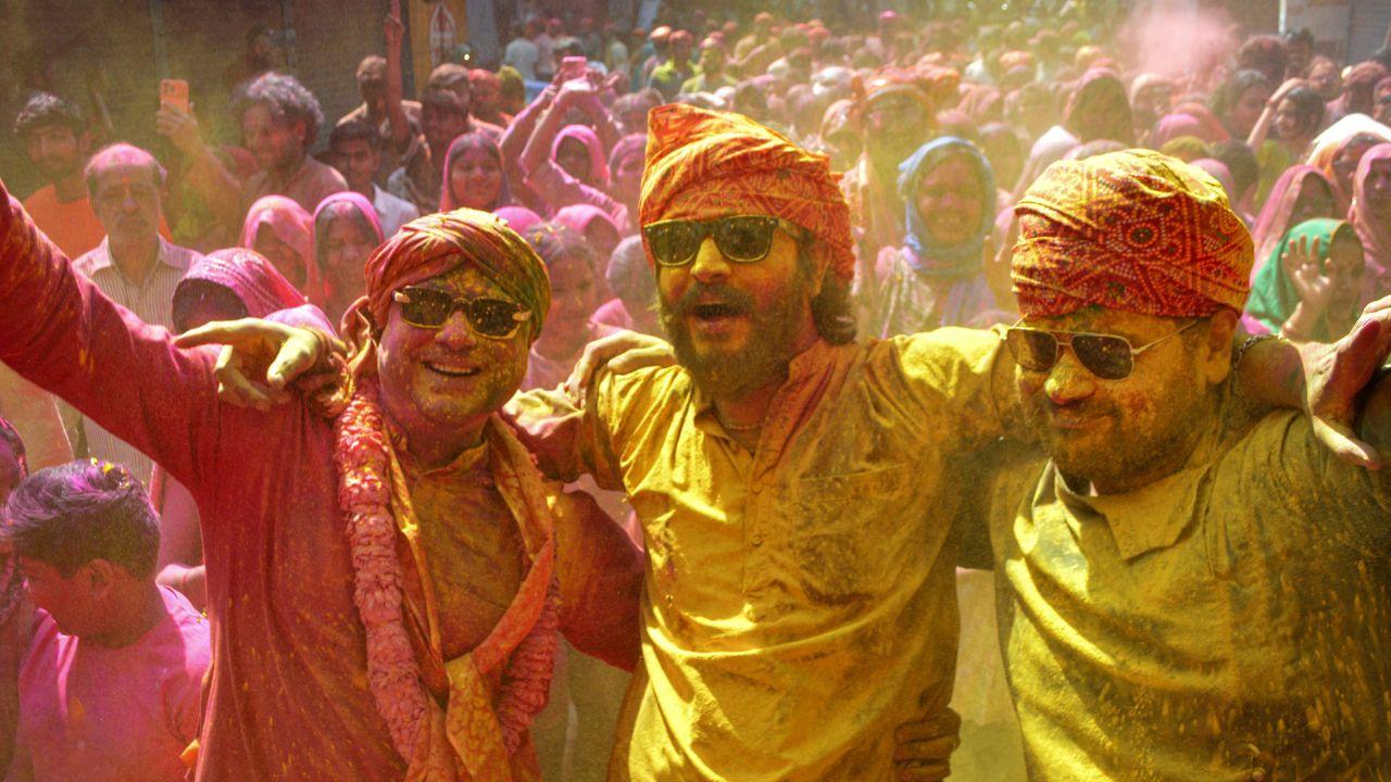 People celebrate by applying colours on each other, playing with water, enjoying sweets like gujiya, and gathering with family and friends