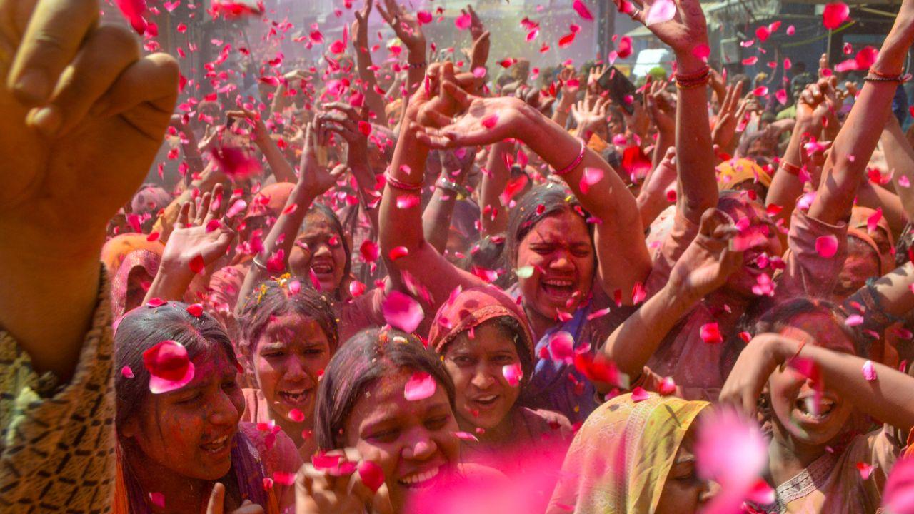 Flower petals rain down during Holi celebrations, adding fragrance to the vibrant scene