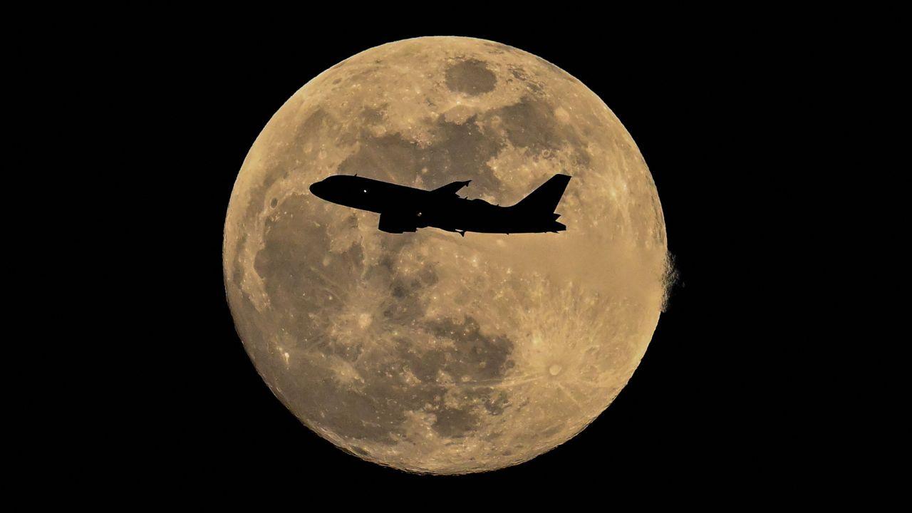 A Lufthansa Airbus A319 jets past the bright moon over Frankfurt, Germany, on the eve of the March full moon