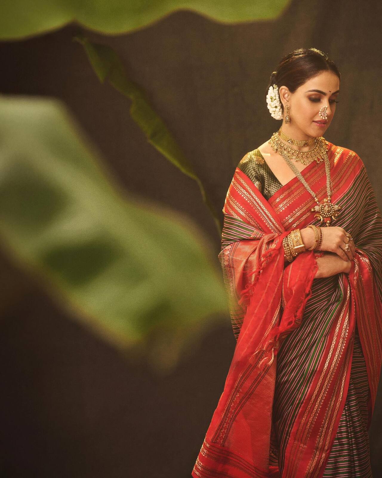 Genelia Deshmukh goes full traditional in a classic red Paithani saree, paired with layered jewellery, oxidised jhumkas, a crescent nath and choodas. Her sleek bun adorned with fresh gajras completes the look.