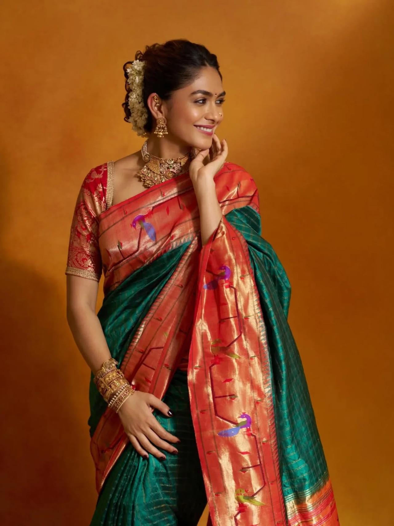 Mrunal aced Marathi Mulgi look in a dual-toned Paithani saree featuring traditional checks and vibrant peacock motifs, a hallmark of Maharashtrian craftsmanship. The rich weave was paired with a striking red blouse detailed with intricate zari threadwork. 