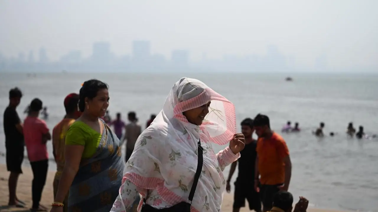 A woman covering her head from the hot sun at the chowpatty