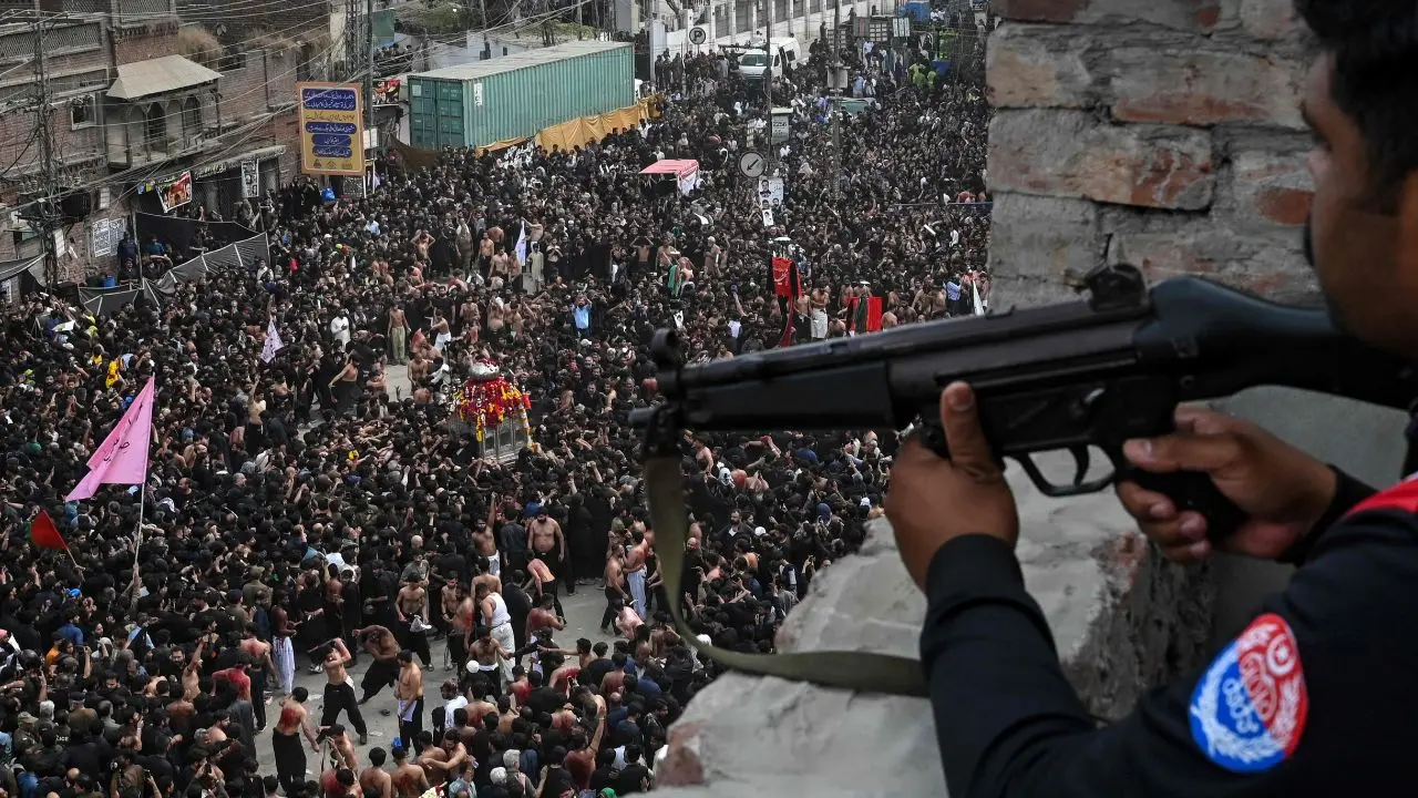 A security personnel keeps watch as Shia Muslims march during a procession marking the death anniversary of Imam Ali, son-in-law of Prophet Muhammad