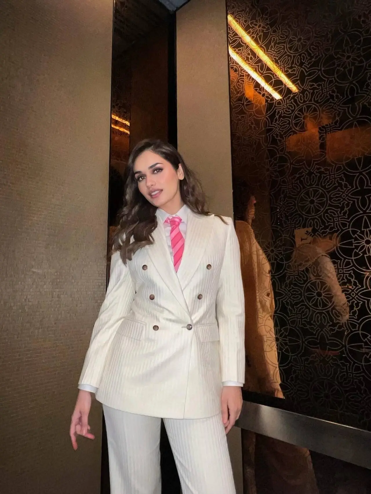 Manushi Chhillar proves that power dressing doesn't always need bold colors, as she stuns in an all-ivory ensemble, featuring a double-breasted blazer, matching trousers, and a pink-toned tie.