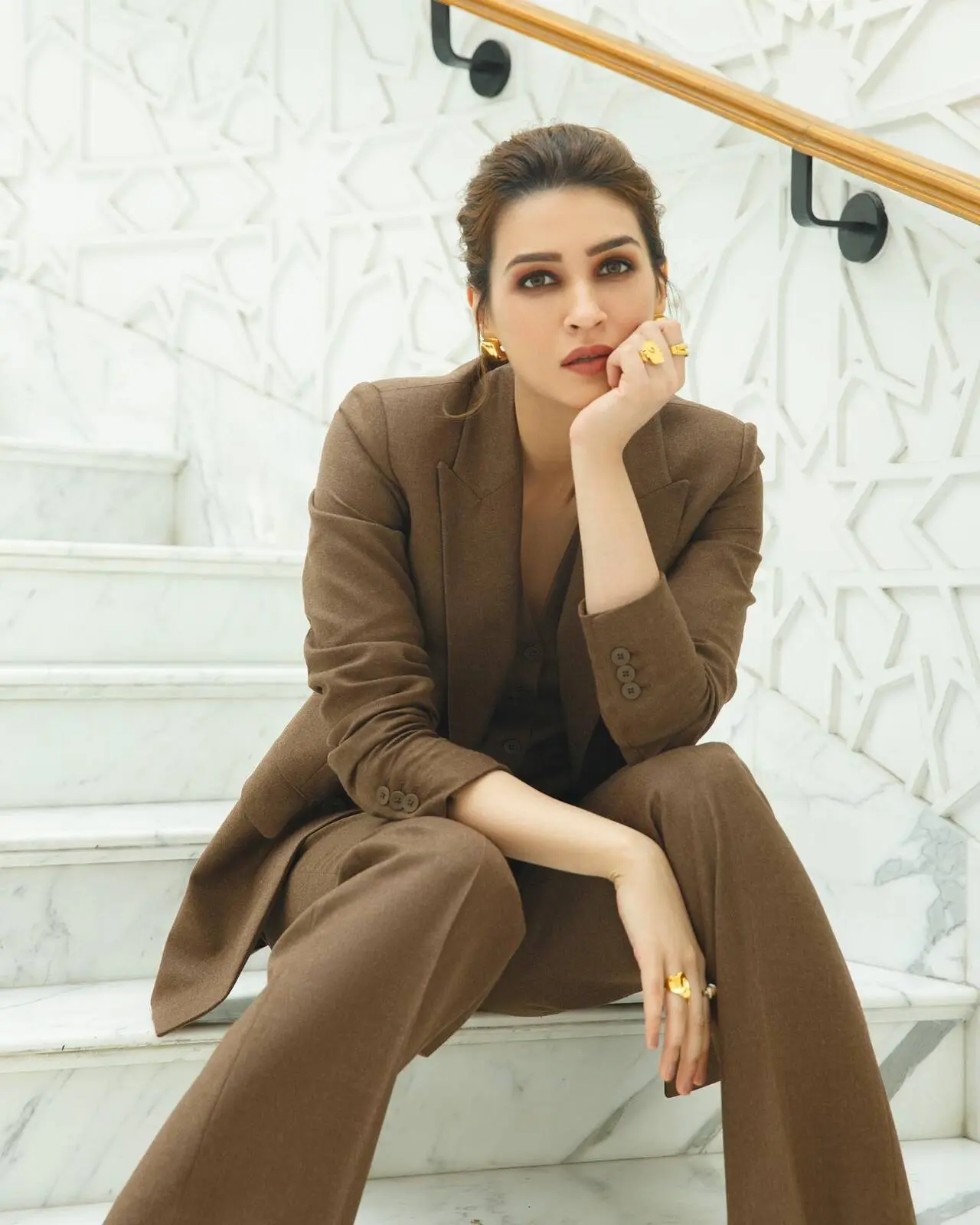 Kriti Sanon in her camel-toned pantsuit styled with bold gold jewelry, demonstrates that power dressing doesn't have to be predictable. 