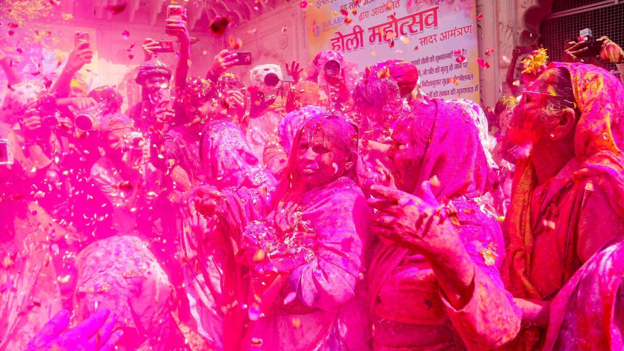 Men, women, and children dance together, their faces smeared with colours as festive cheer fills the air