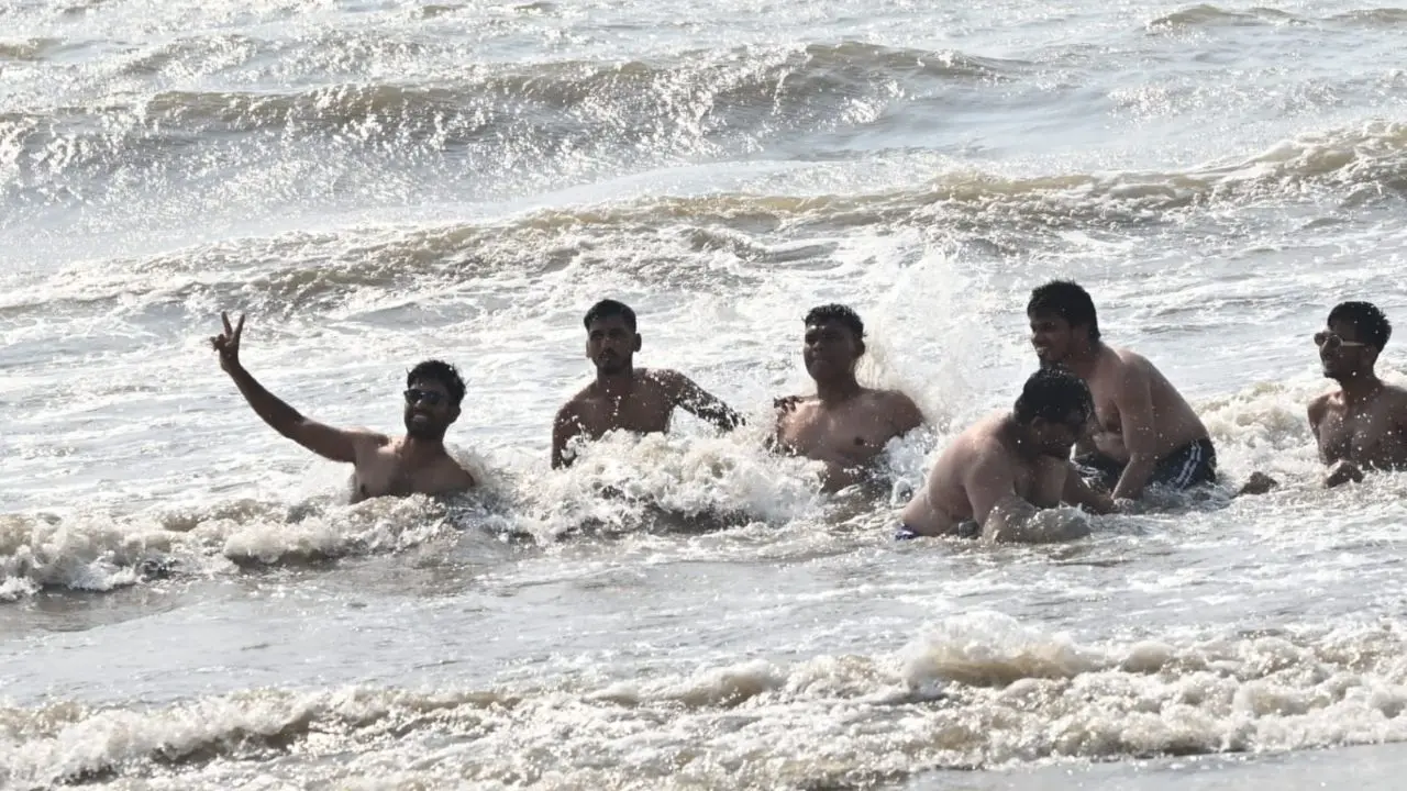 People relax and play in the waves under the blazing sun as IMD forecasted temperature of 36 degree Celsius