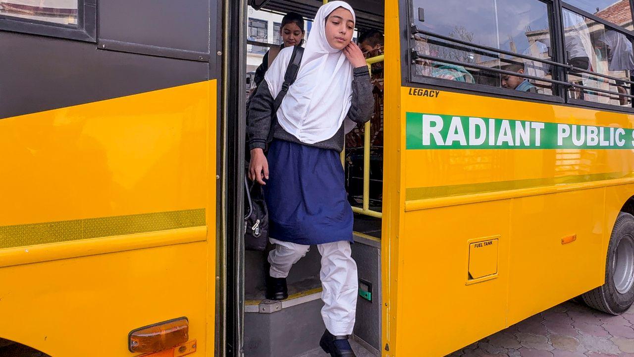 <p>A student steps off a school bus as educational institutions reopen in the district in Anantnag</p>