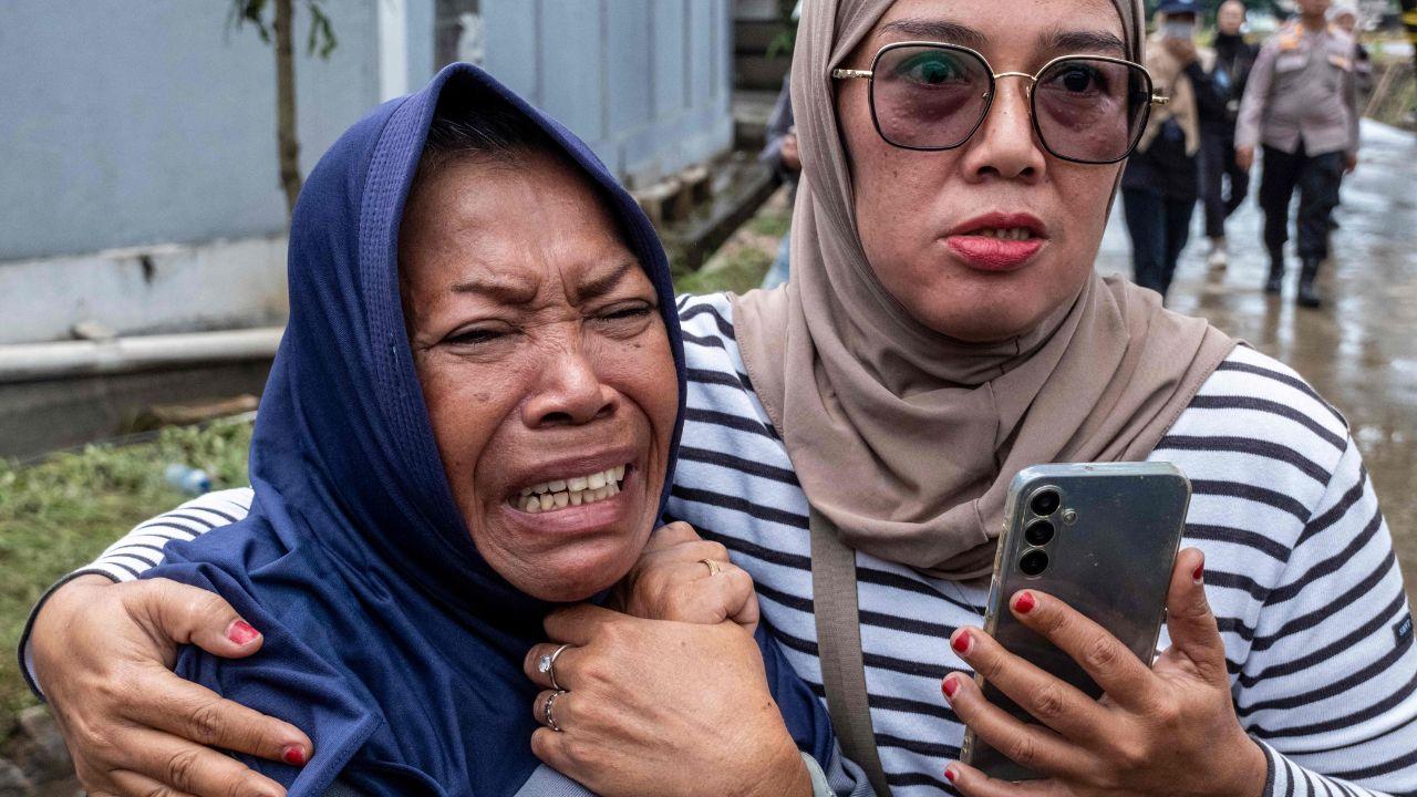 A woman breaks down upon finding the body of her loved one, from within the heaps of waste