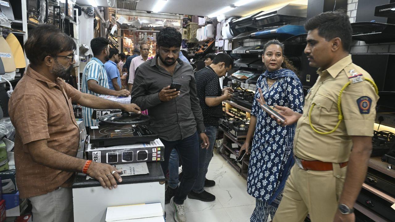 A policewoman keeps an eye on the bustling crowd at Dadar market as customers rush to buy affordable electric alternatives, unwilling to risk going without a functional kitchen amid cylinder shortages