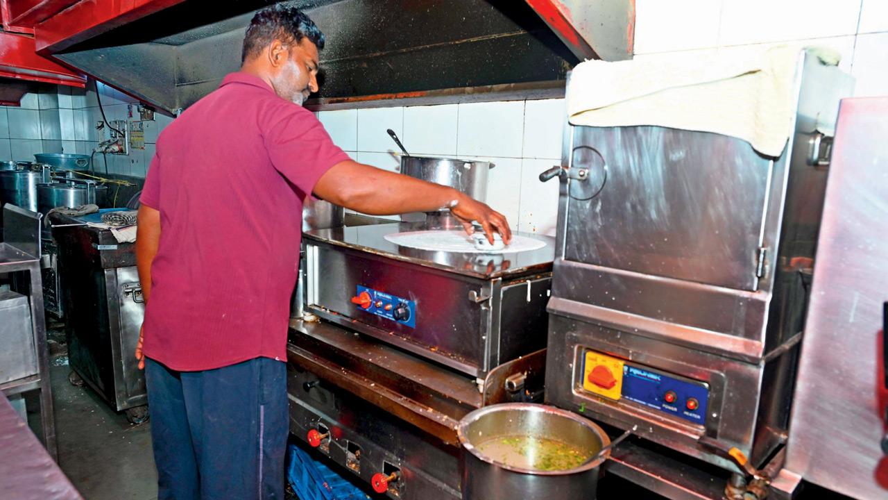 A chef prepares a dosa on an electric tawa
