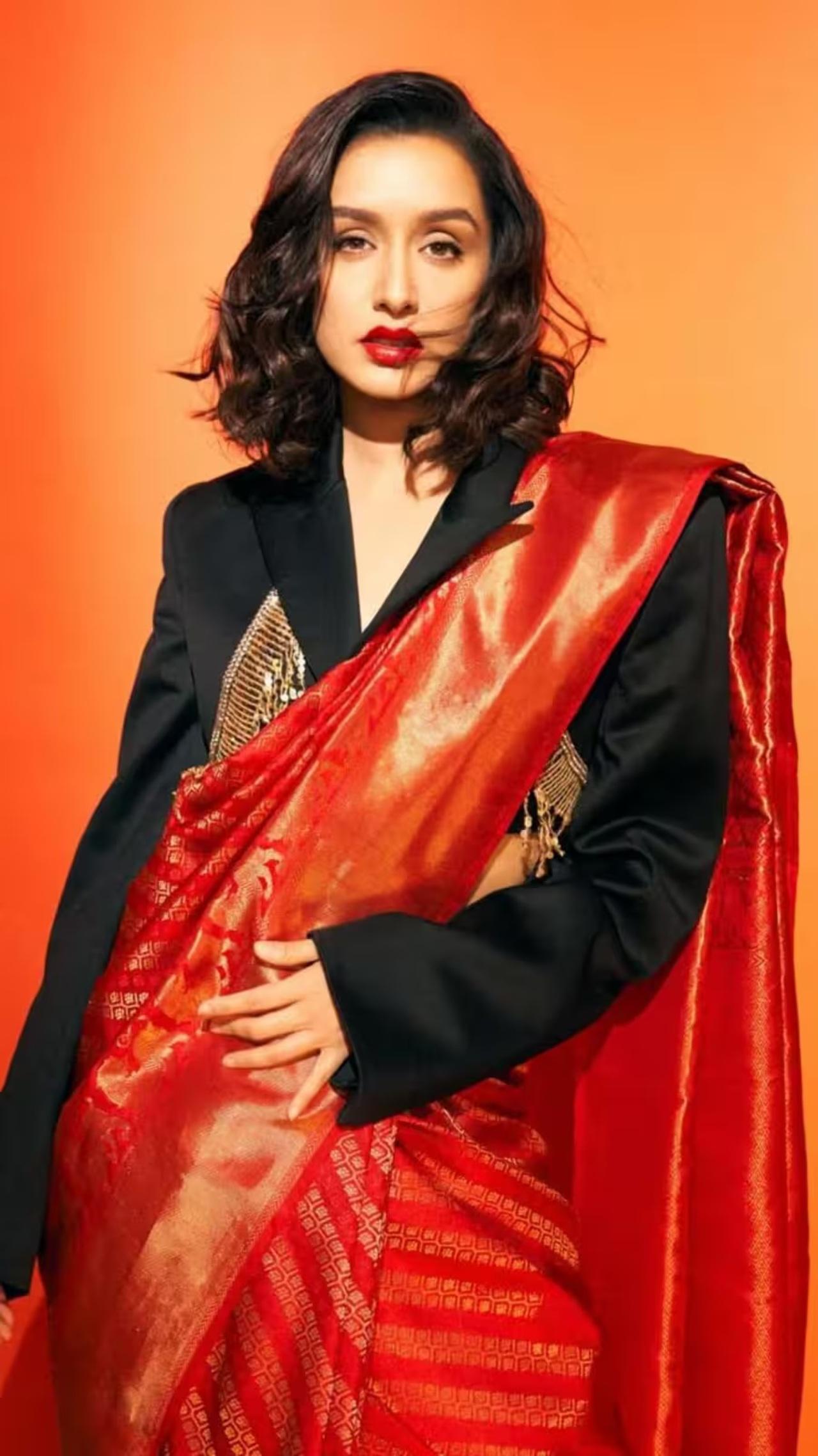 Shraddha creates a striking fusion by pairing a traditional red Banarasi saree with a contemporary black blazer. Her short hair and red lips bring power and charisma.