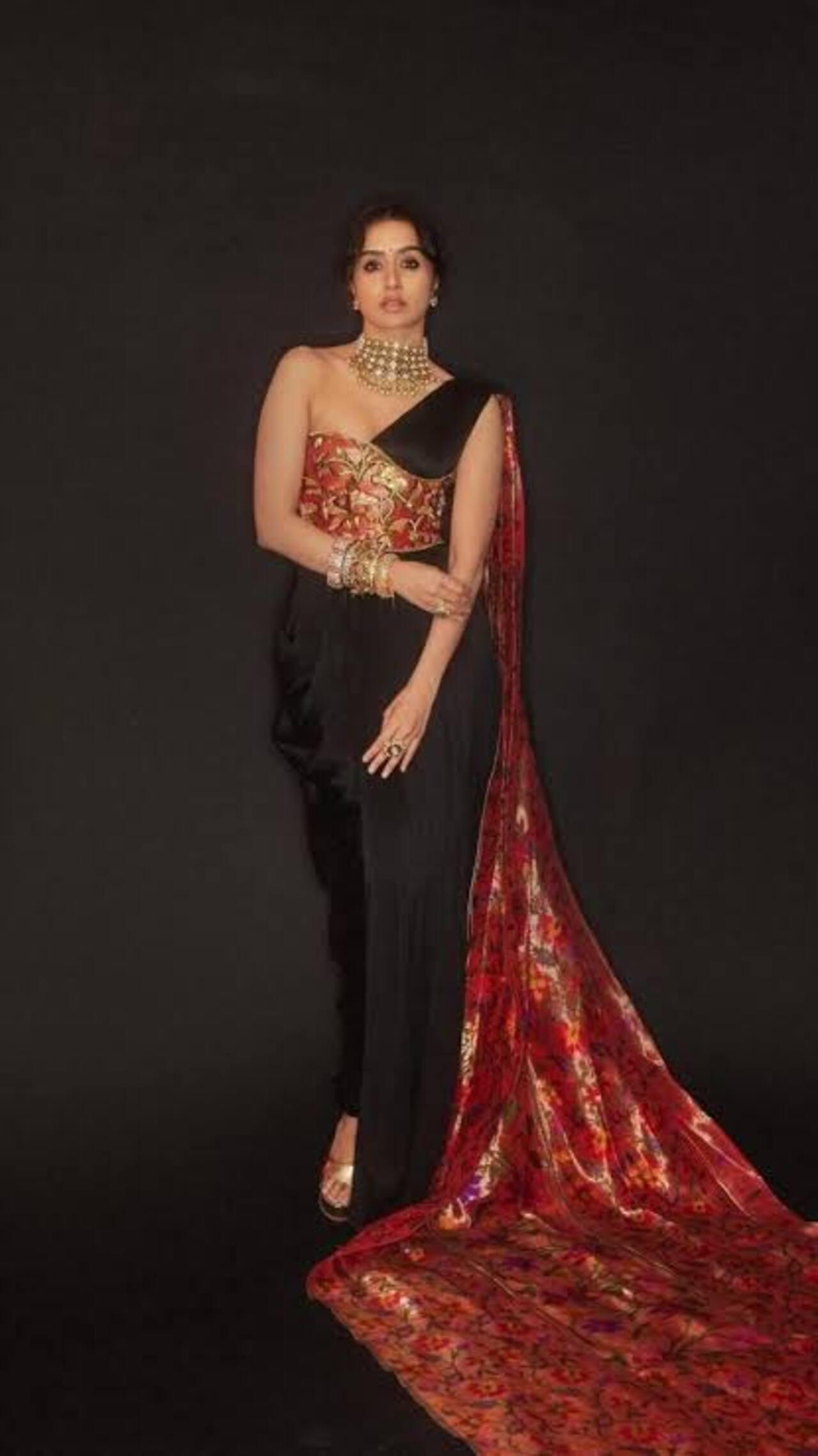 Shraddha redefines saree drapes in this traditional Paithani sari, which is redesigned to give it a western twist. It consists of a black jumpsuit paired with a Paithani sari draped over her chest. 