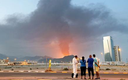 Foreign workers look at a tall plume of black smoke ascend following an explosion in the Fujairah industrial zone on March 3. pics/AFP