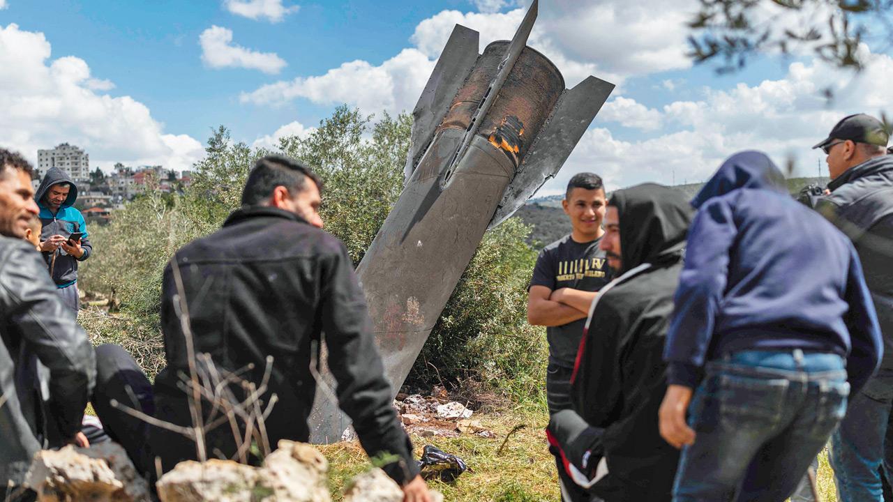 Palestinians gather near an Iranian missile remnant in the Occupied West Bank. Pics/AFP