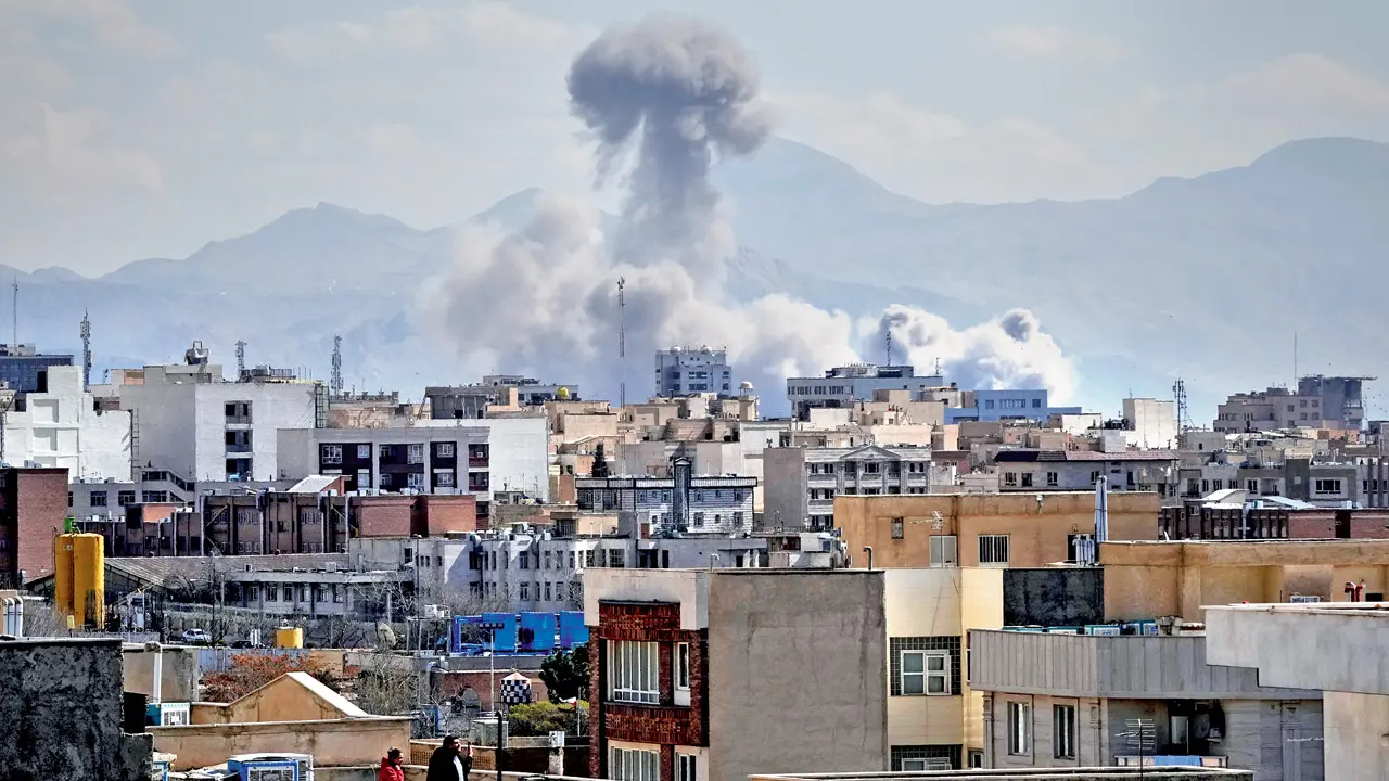 People watch from a rooftop as a plume of smoke rises after a strike in Tehran. Pic/AFP