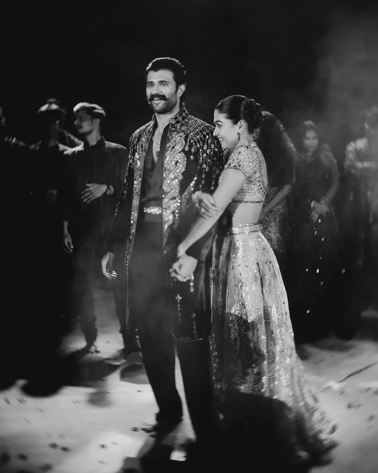 Rashmika holds on to Vijay's arm in this picture from their sangeet night as they look at presumably their loved ones performing.