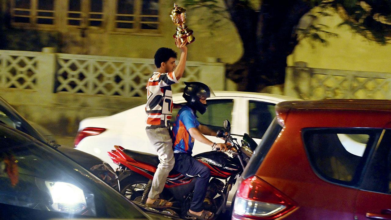 A fan holding a trophy to celebrate India's World Cup win