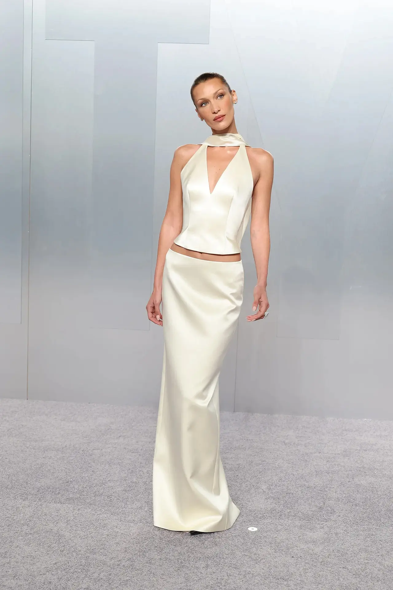 Bella Hadid turned heads in a butter-yellow satin two-piece set by Prada. The look featured a flowing maxi skirt paired with a plunging halter-neck top and a satin neck scarf. She completed the ensemble with elegant jewellery pieces from Chopard.