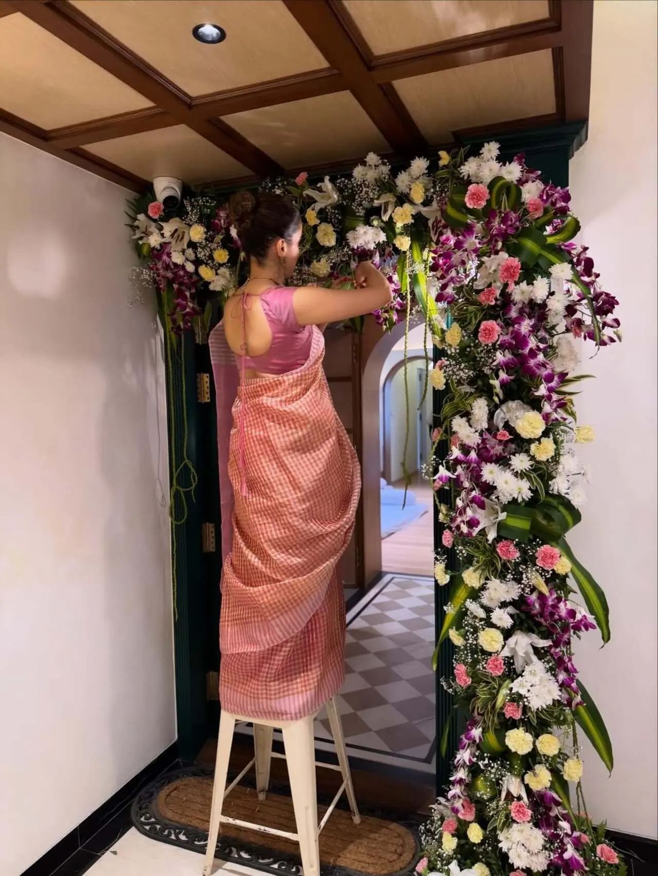 Floral entrance décor: The doorway is decorated with vibrant flowers in white, pink, and purple, giving a festive housewarming feel.