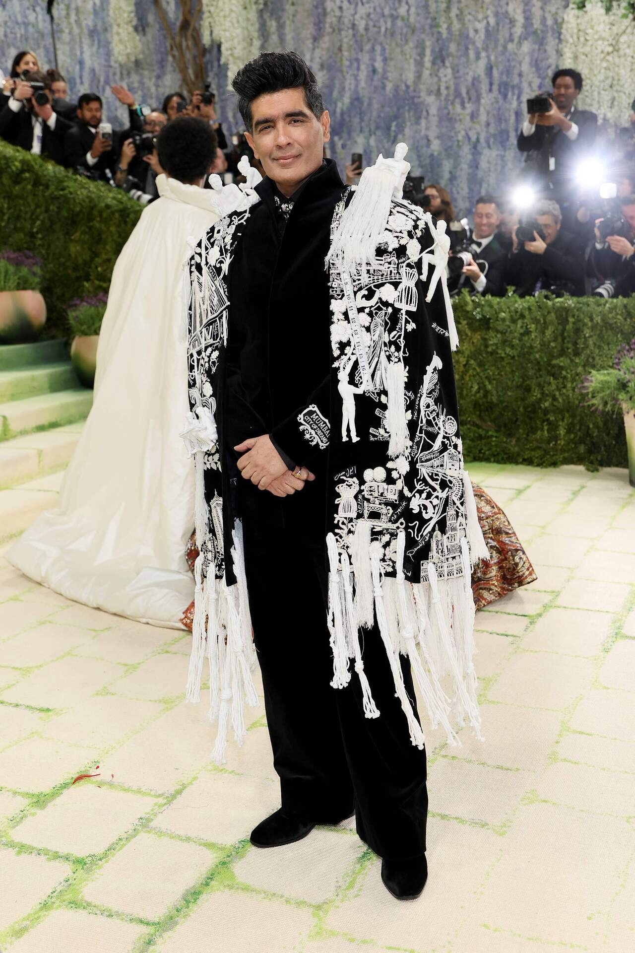 This time at MET, Manish Malhotra paid a tribute to Mumbai and the craftsmen of India through his meaningful ensemble. He donned a Mumbai-inspired couture, consisting of a black bandhgala layered with a 960-hour cape crafted by 50 artisans.