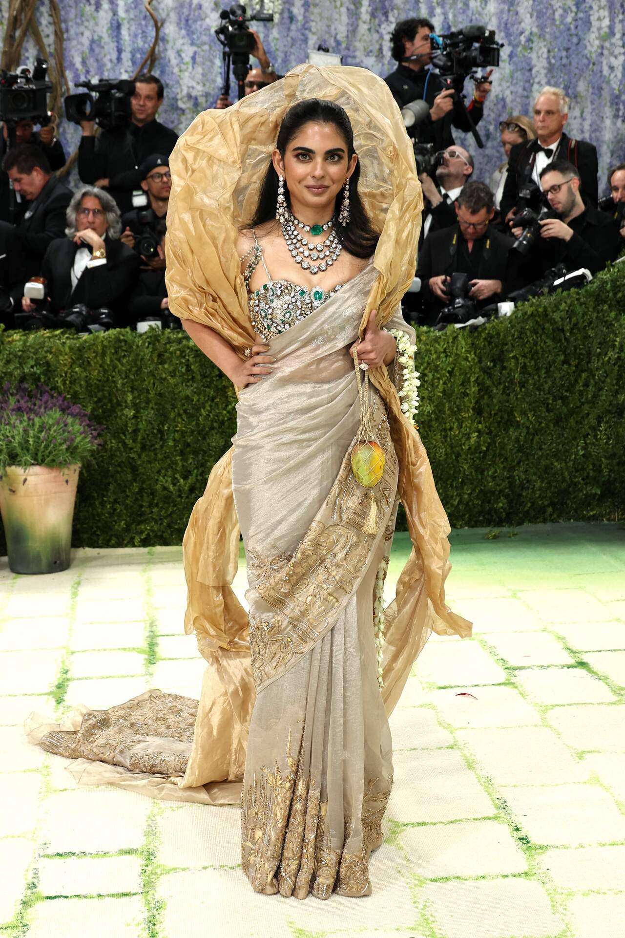 Isha Ambani wore a custom couture saree by Gaurav Gupta, created in collaboration with Swadesh artisans. The saree was woven with threads of pure gold and featured hand-painted pichwai-inspired motifs in soft gold and earthy tones. However, what caught the eye of everyone was her mango-shaped sculpture by artist Subodh Gupta. The accessory served as a nod to Indian heritage and added an artistic element to her overall appearance.&nbsp;
