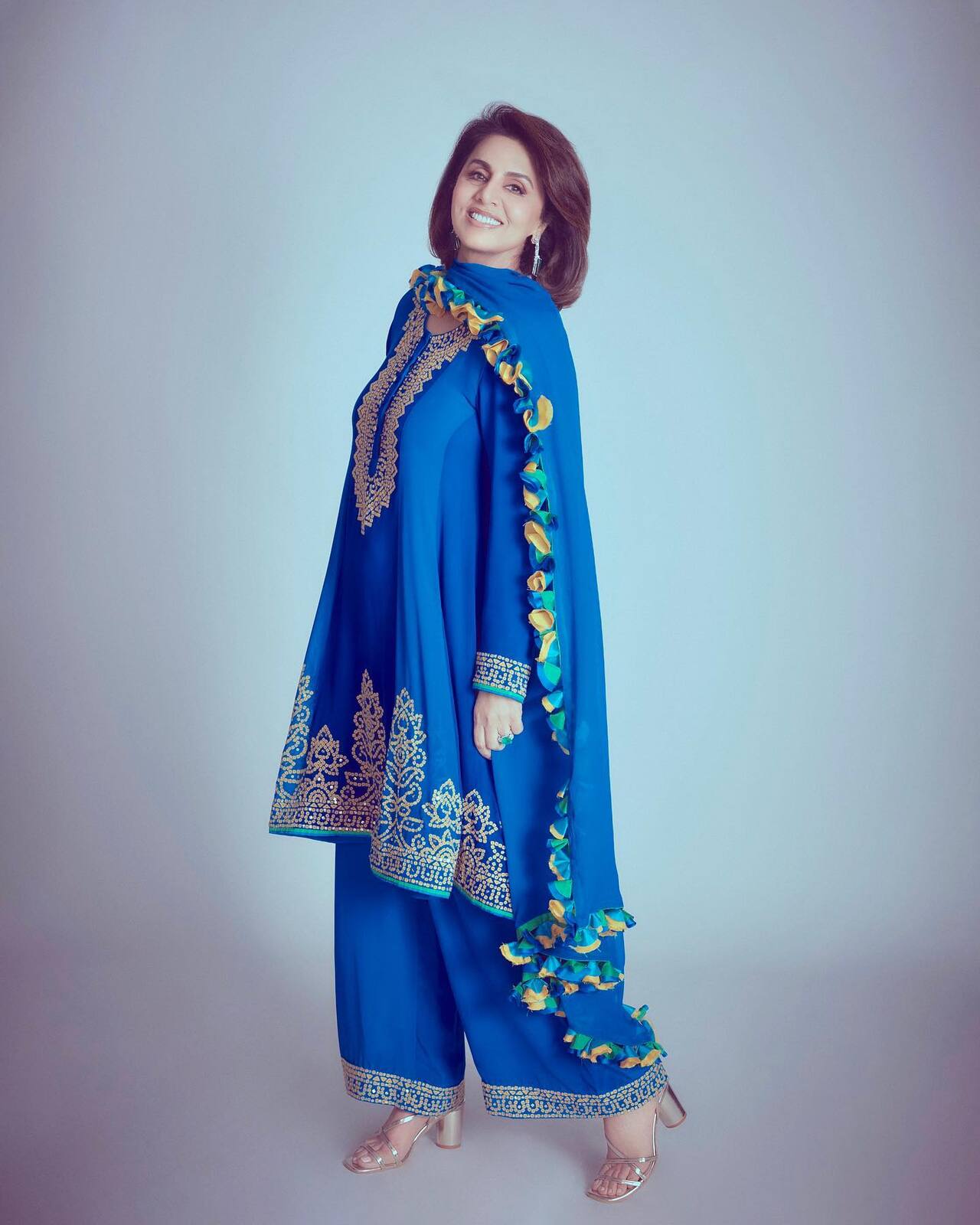 Neetu Kapoor stuns in this electric blue ethnic set, featuring a short kurta and wide-leg trousers adorned with intricate gold gota patti work and traditional motifs.