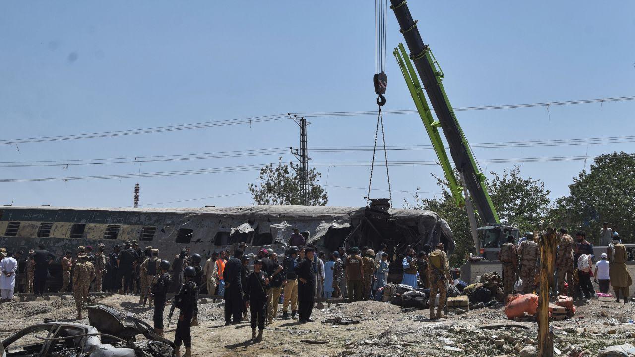 Armed security forces guard the blast site while cranes are brought in to remove heavily damaged train coaches from the railway tracks Armed security forces guard the blast site while cranes are brought in to remove heavily damaged train coaches from the railway tracks