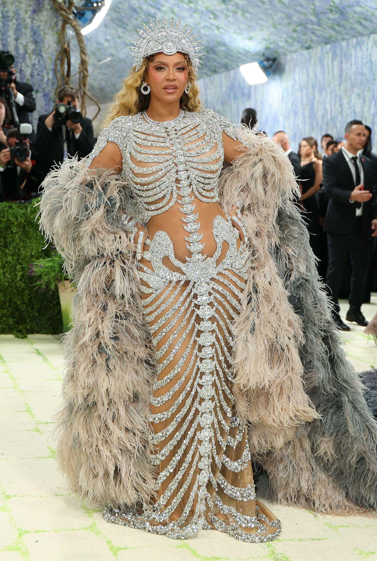 Beyonce is back! The global superstar made a stunning return to the Met Gala 2026 red carpet. The 44-year-old singer wore a bold and eye-catching outfit designed by Olivier Rousteing. She chose a crystal-covered "naked" gown featuring a skeleton-inspired design, with detailed work even on the hands. The look was paired with a dramatic blue and white feathered cape, a sparkling headpiece, and heavy diamond jewellery by Chopard. Her long curls completed the look.