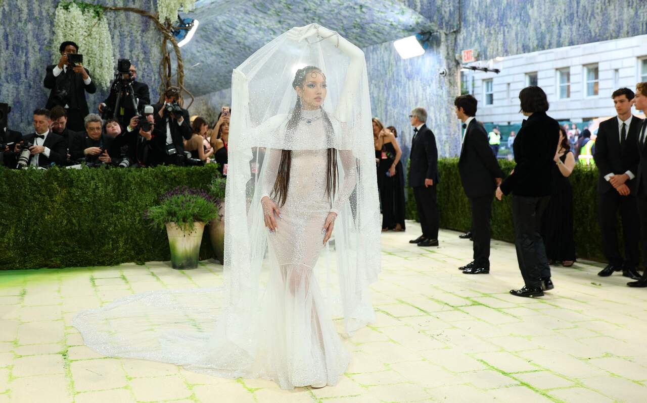 BLACKPINK star LISA, aka Lalisa Manobal, wore a striking outfit designed by Robert Wun. The dress featured a tent-like structure with 3D arms holding up a sheer white veil, making it look like she was standing inside a moving piece of art. The 3D arms were placed in traditional Thai dance poses.