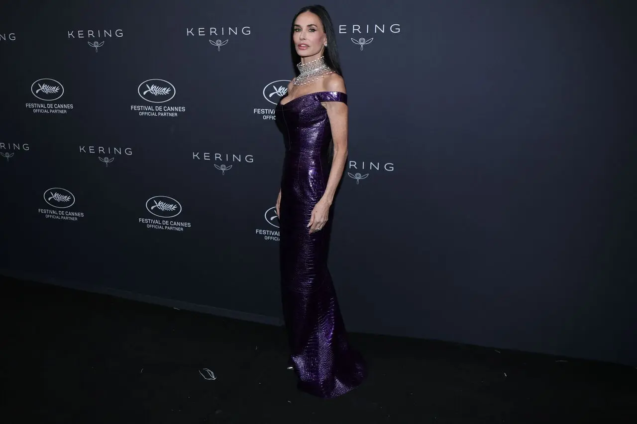 Demi Moore turned heads in a striking purple vinyl crocodile leather gown featuring an elegant off-shoulder neckline as she posed at the photocall for the 2026 Kering Women in Motion Awards during the Cannes Film Festival.&nbsp;